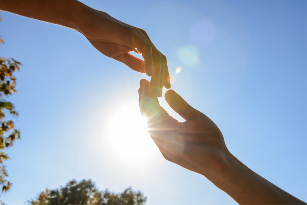 Two hands reaching out for each other as compassion to self-criticism